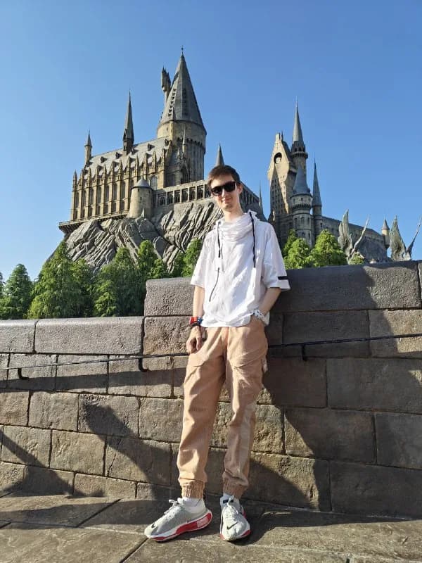 Антон у каменного парапета, за спиной — замок Хогвартс в Universal Studios Japan