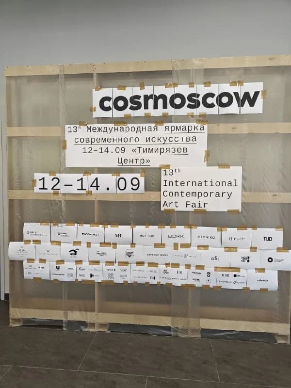 Навигационный стенд Cosmoscow из необработанной фанеры: логотип ярмарки и карточки участников