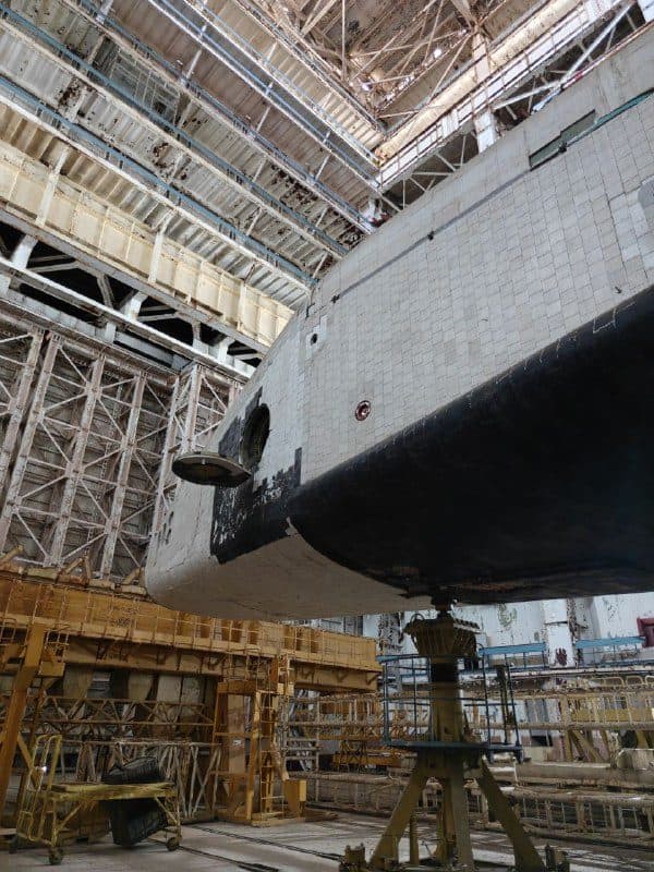 Нос второго «Бурана» в полутёмном ангаре, корабль подвешен над полом