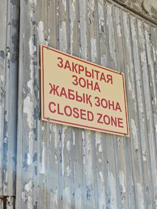 Табличка на воротах: «Закрытая зона / Жабық зона / Closed zone»
