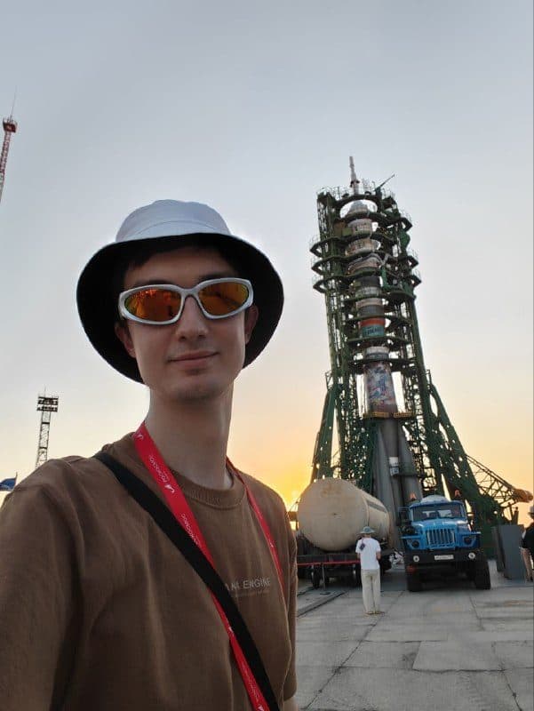 Антон на фоне ракеты в закатном свете, за спиной фермы стартового комплекса