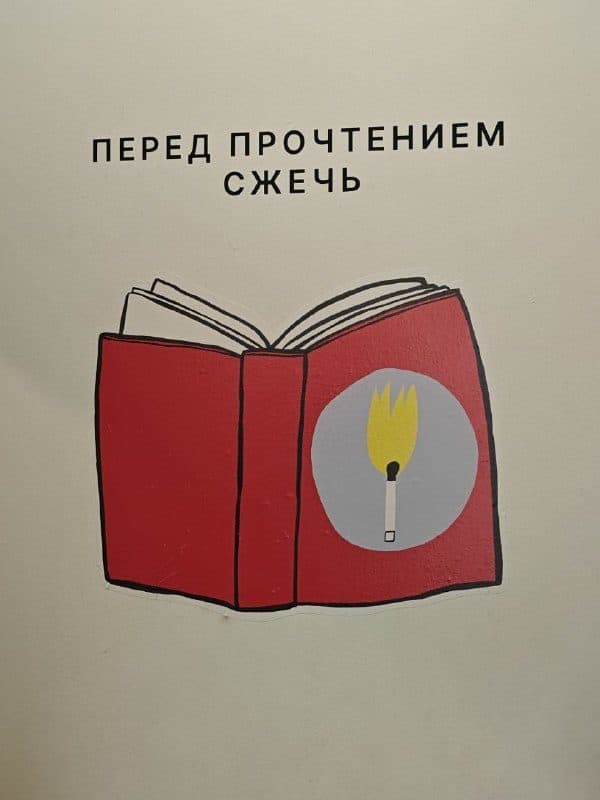 Рисунок на стене: раскрытая книга с вилкой вместо закладки и надпись «Перед прочтением сжечь»