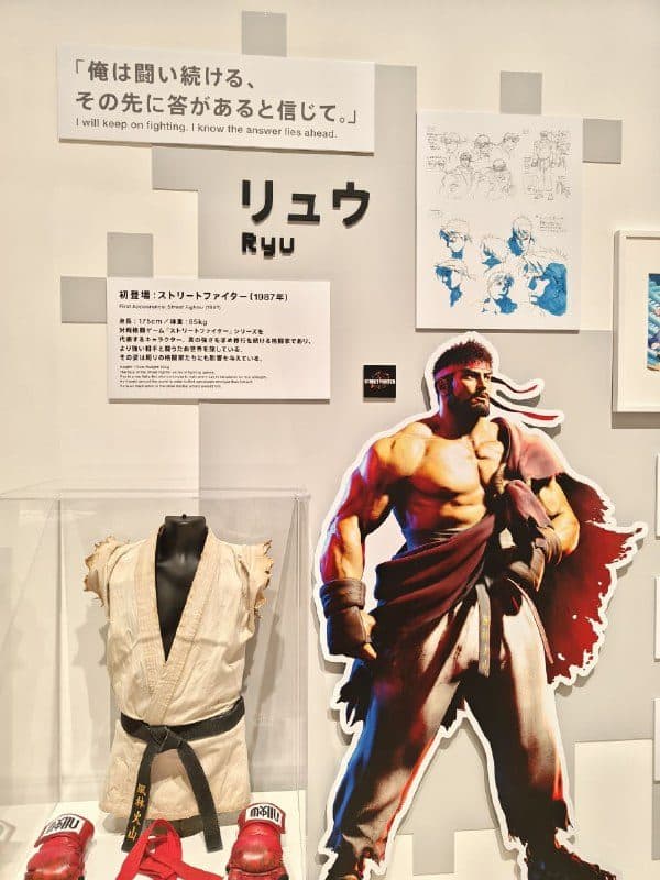Витрина с кимоно и перчатками Рю из Street Fighter рядом с его ростовым изображением