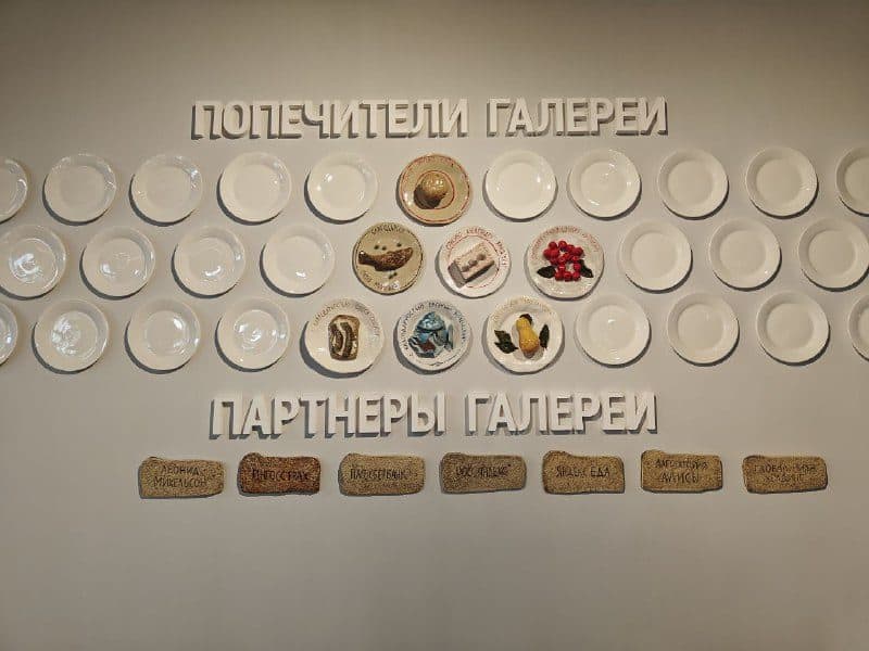 Стена попечителей галереи: тарелки с едой вместо табличек