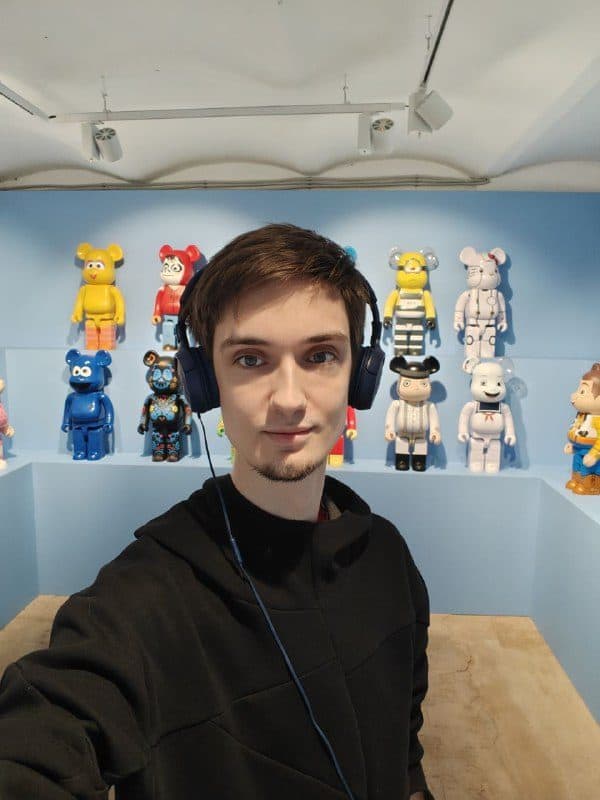 Антон в наушниках у стены с Bearbrick