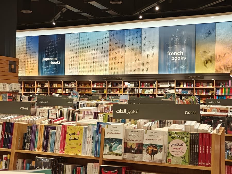 Зал магазина: указатели Japanese books и french books над стеллажами, ниже — полки с арабскими и русскими книгами